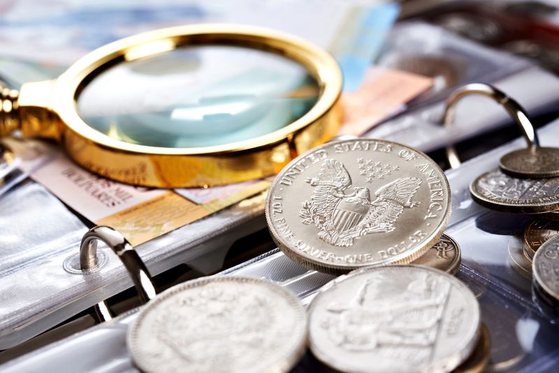 Silver dollars and old U.S. banknotes in a collector album, the kind of coins a Dallas coin dealer buys