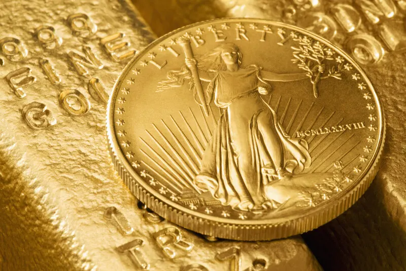 Polished gold bullion bars and a gold coin