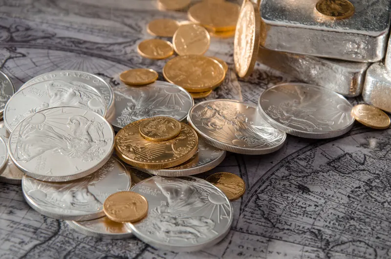 Gold and silver coins with bars on a world map