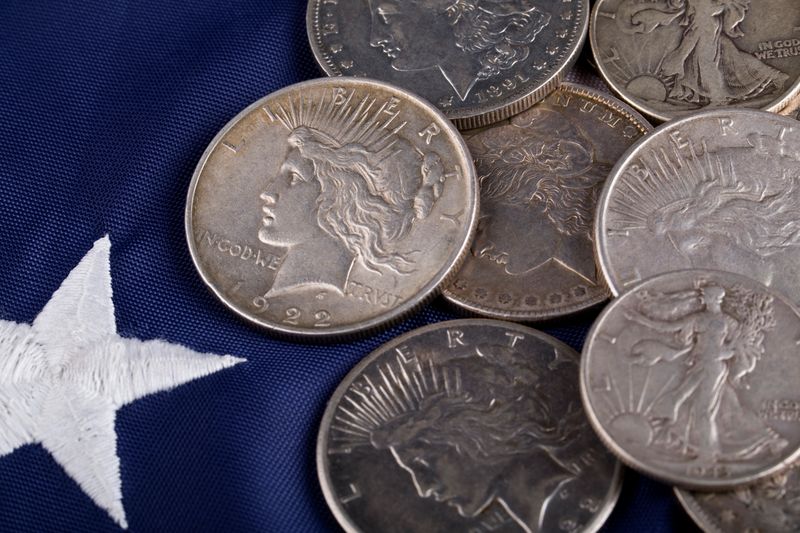 Morgan and Peace silver dollars on a U.S. flag, ready to sell in Dallas